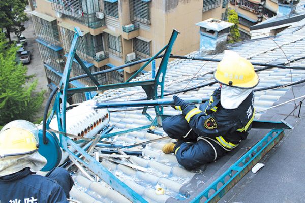 暴雨后楼顶太阳能热水器破碎悬空 消防员迅速