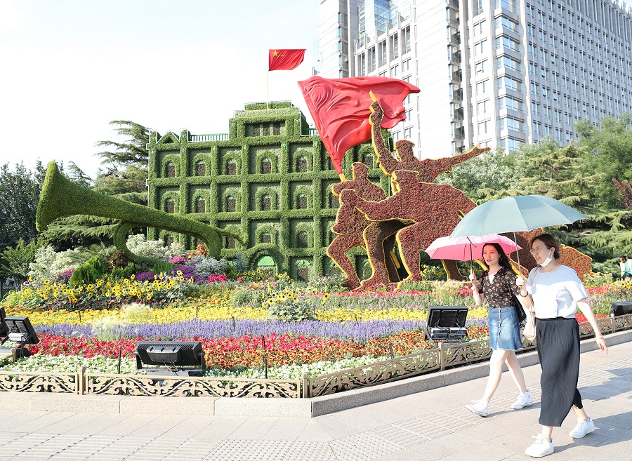 6月22日,行人经过东单东北角以"建军大业"为主题的立体花坛.