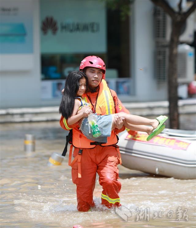 7月24日,在郑州市中牟县白沙镇,湖北孝感消防救援人员帮助1名女孩涉水