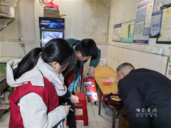 社区工作人员检查辖区商户消防器材是否安全有效。.jpg