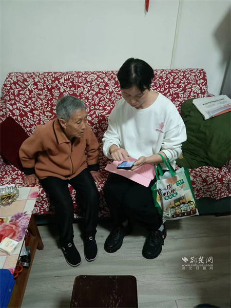 社区工作人员正在帮助石月娥进行社保年审资格认证。.jpg