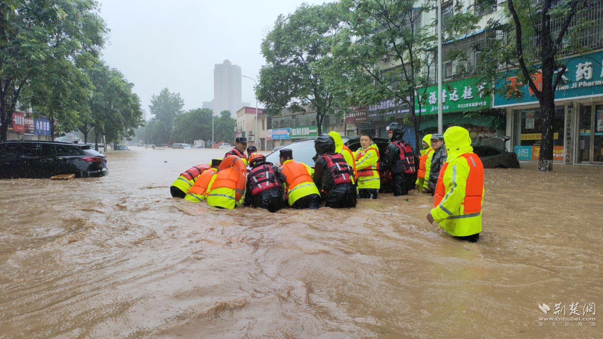 7月14日，湖北省丹江口市城区路面大面积严重积水，一辆黑色SUV轿车被洪水冲至马路中央无法动弹。为最大程度减少群众损失，当地民警