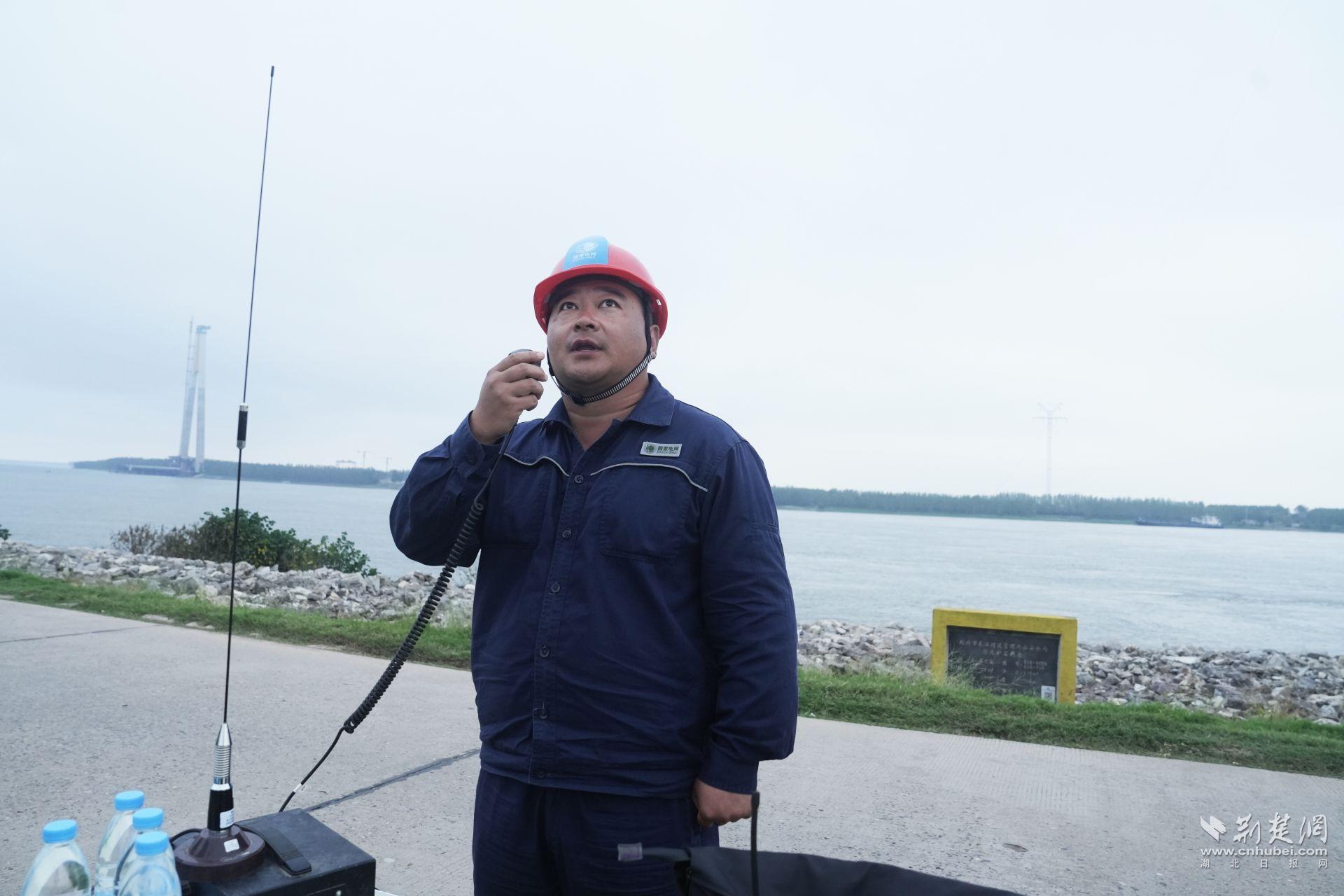 图2：地面收线指挥人员李鹏正在进行江面旧线回收部署。.JPG.JPG
