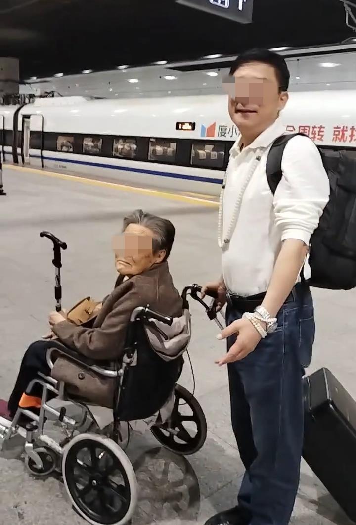 一名60多岁的男子推着轮椅上的94岁母亲登上了火