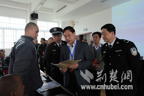 在服刑人员学习功能室内,司法厅副厅长程颖查看罪犯学习笔记,并询问学习情况