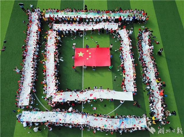 9月26日,宣恩县的小学生在百米长卷上绘出五星红旗,天安门,长城,火箭