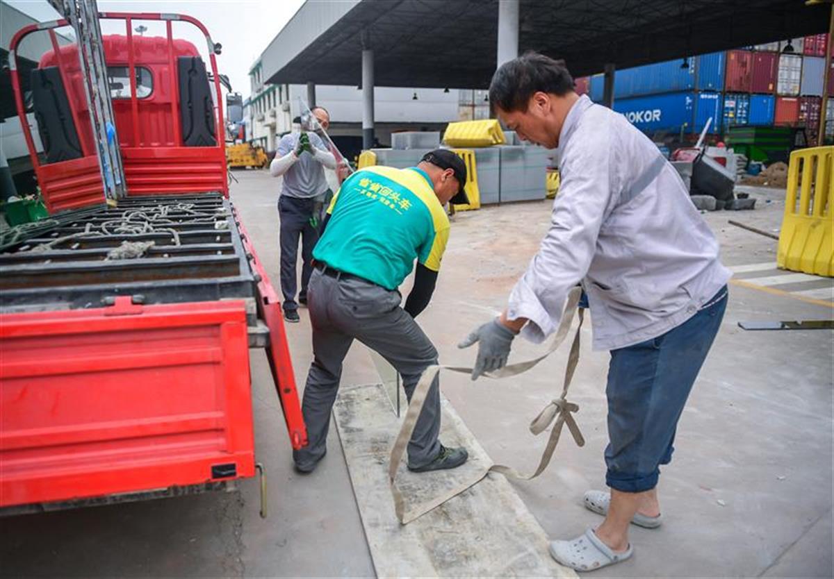 在武汉阳逻港的一装修工地,4名工人师傅正在搬运大块头装修玻璃,只见