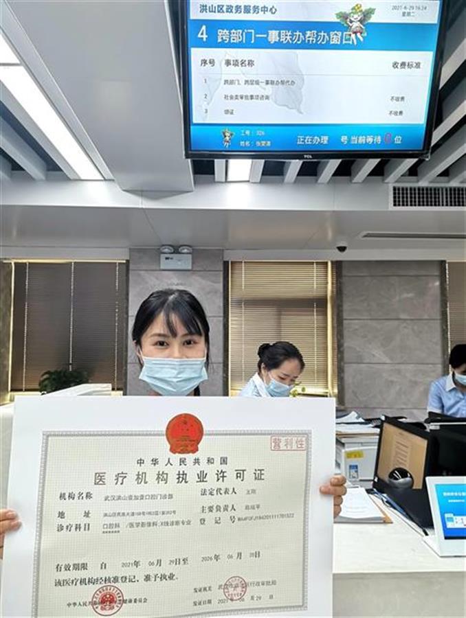 在洪山区政务中心8楼便民服务区,该门诊部负责人在专窗帮代办工作人员