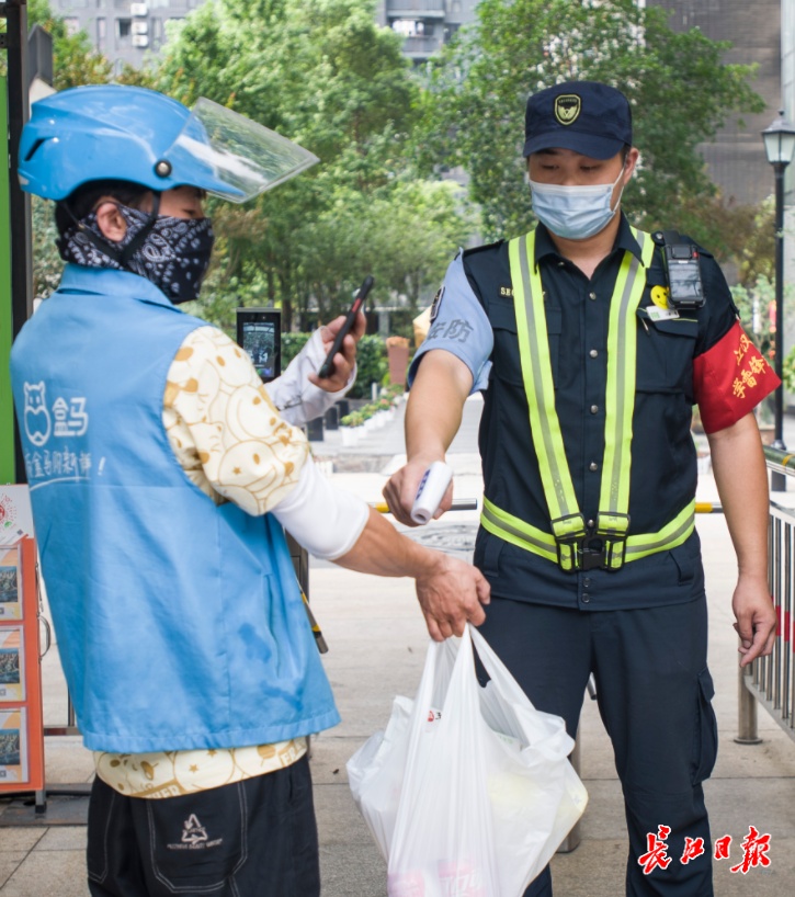 8月2日,武汉一小区工作人员对进入小区外来人员,登记,扫码,测体温.