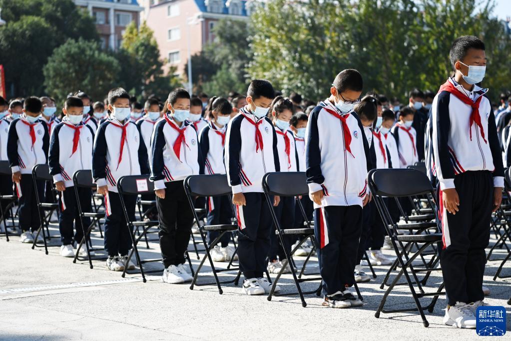 18日,在侵华日军第七三一部队罪证陈列馆广场,少先队员在警报声中默哀