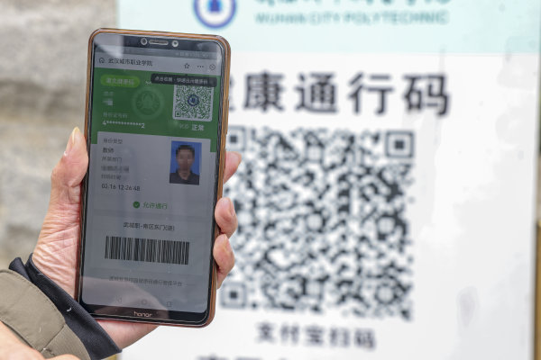 门口设置了测温刷脸通道,一名工作人员出示健康码,行程码后"刷脸"通行