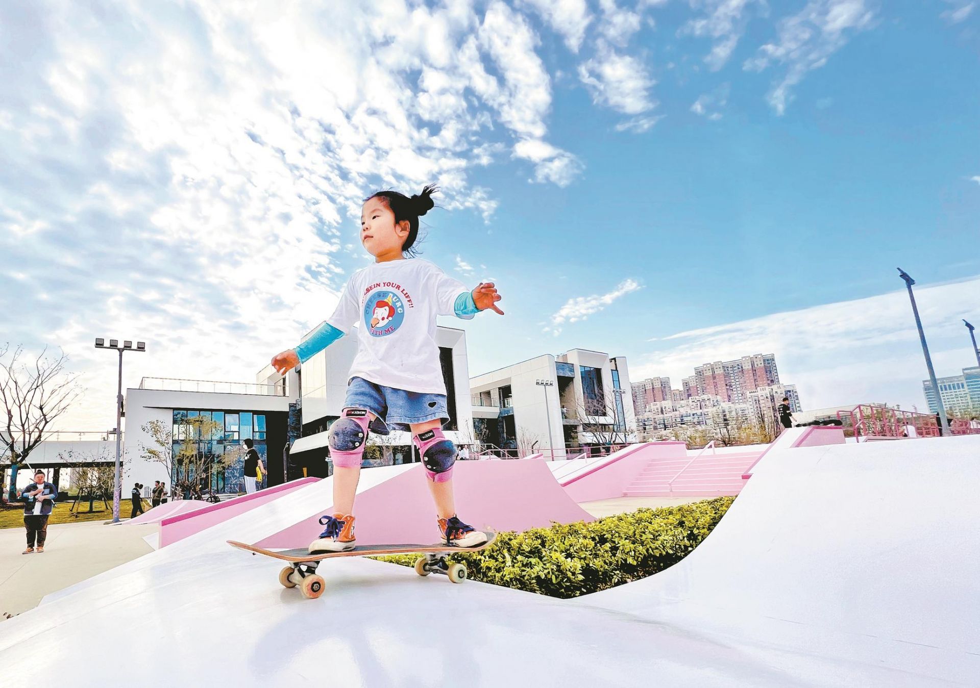 在武汉市东西湖区中央明渠樱花溪公园落樱文化段,踩着滑板,小轮车的