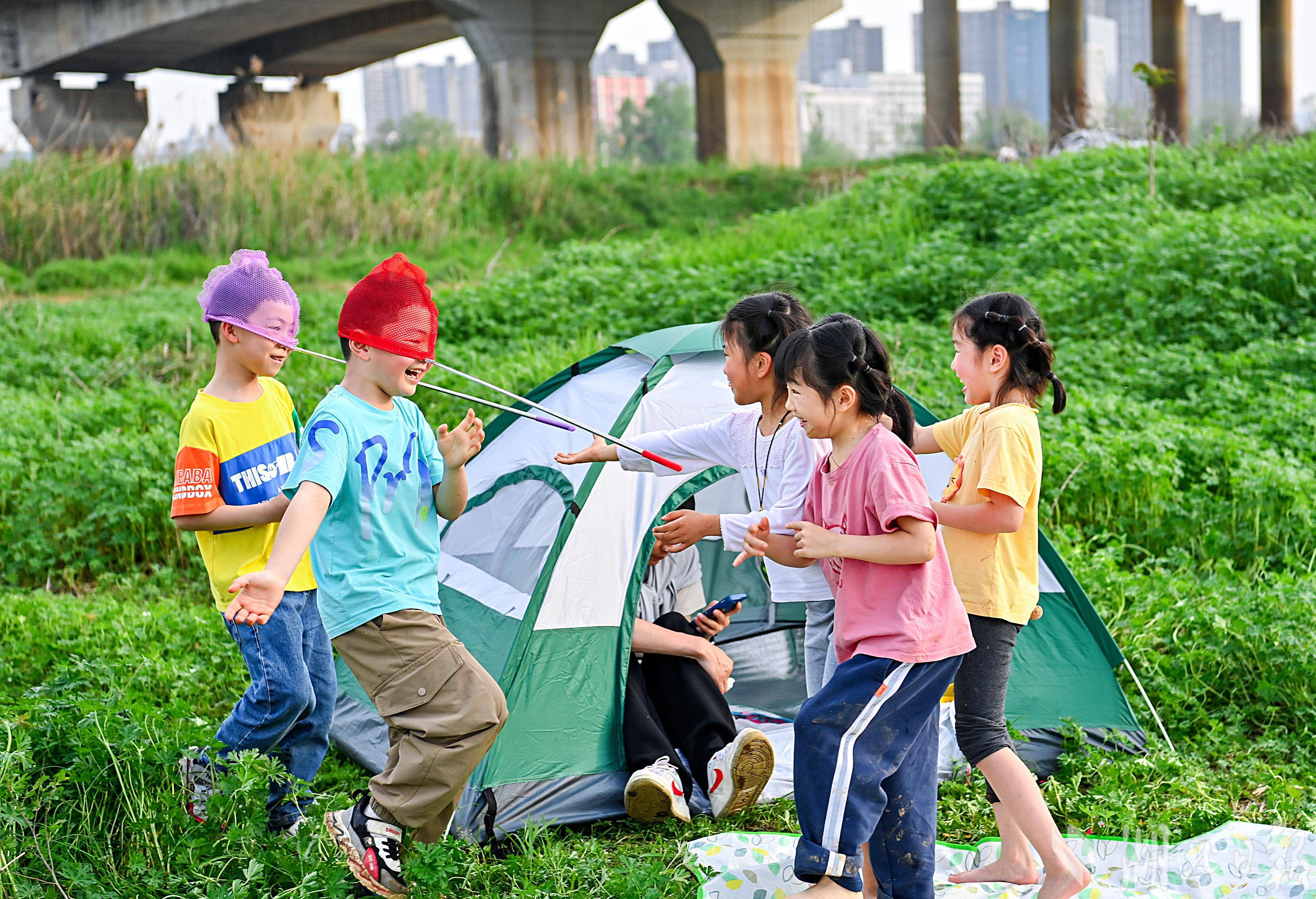 许多市民游客在河滩上支起帐篷,铺上地垫,放风筝,踏青等,置身大自然