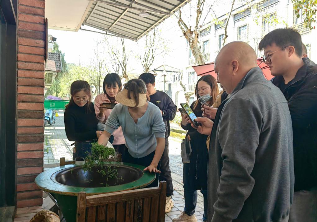 4月9日,来自江苏的游客在黄山茶林场观看炒茶制作.